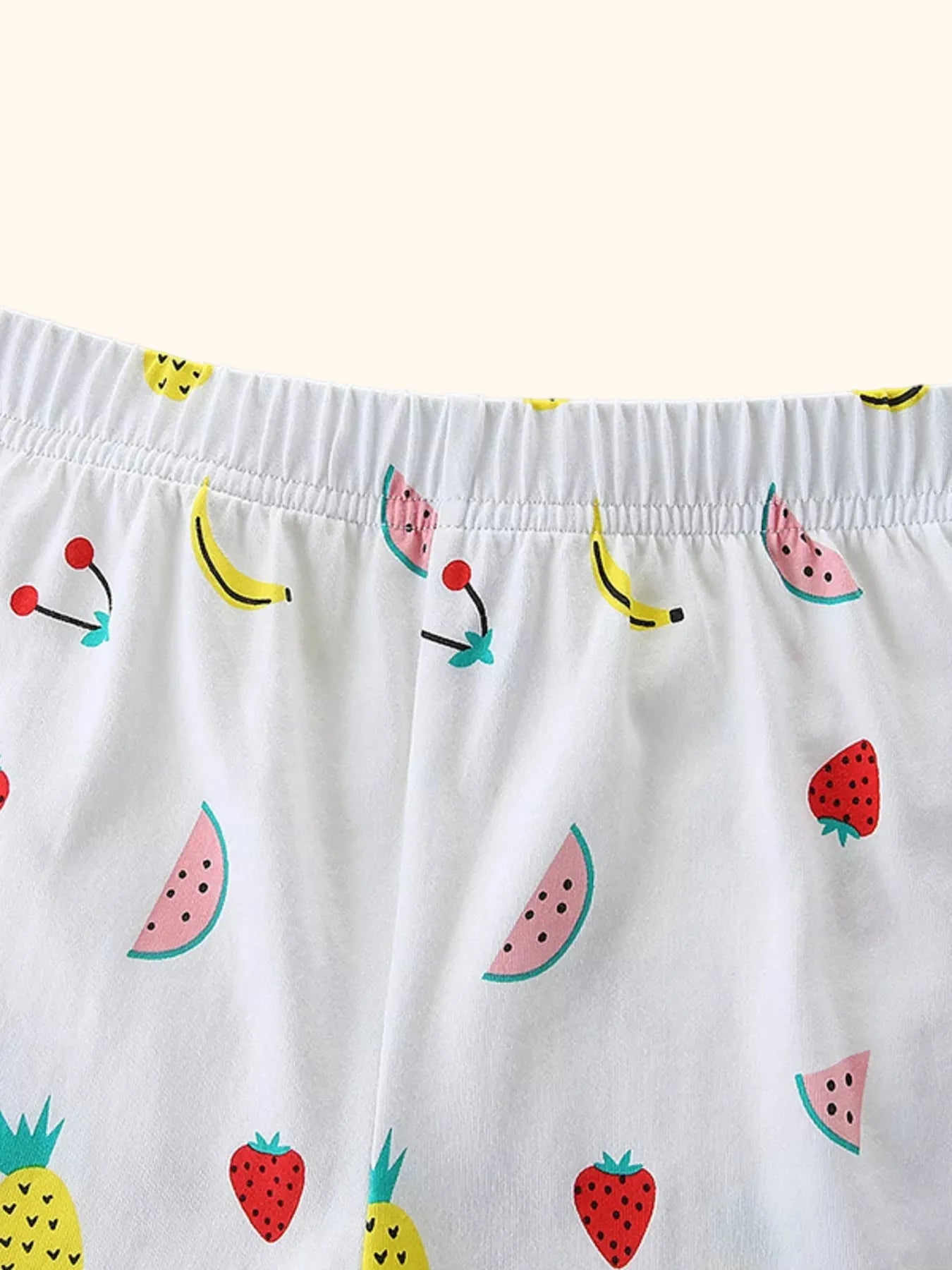 White kids fruit print shorts with pineapple, watermelon, strawberry, banana, and elastic waist, detail view