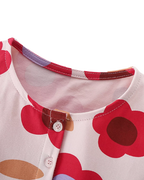 Pink kids floral print dress with round neckline and partial button front, neckline close-up