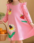 Blush pink kids insect and flower appliqué dress worn by child, front lifestyle view