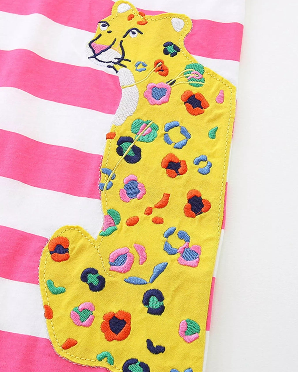 Pink striped kids dress with yellow leopard appliqué pocket and colorful embroidered spots, detail view
